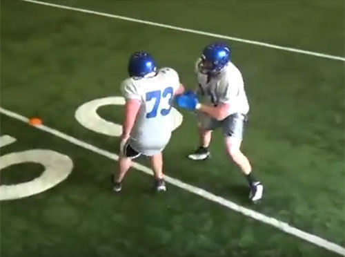 High school offensive lineman practicing lateral footwork using The Muzzle training pads
