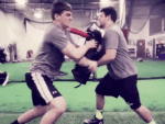 Youth football players practice hand placement using football blocking pad